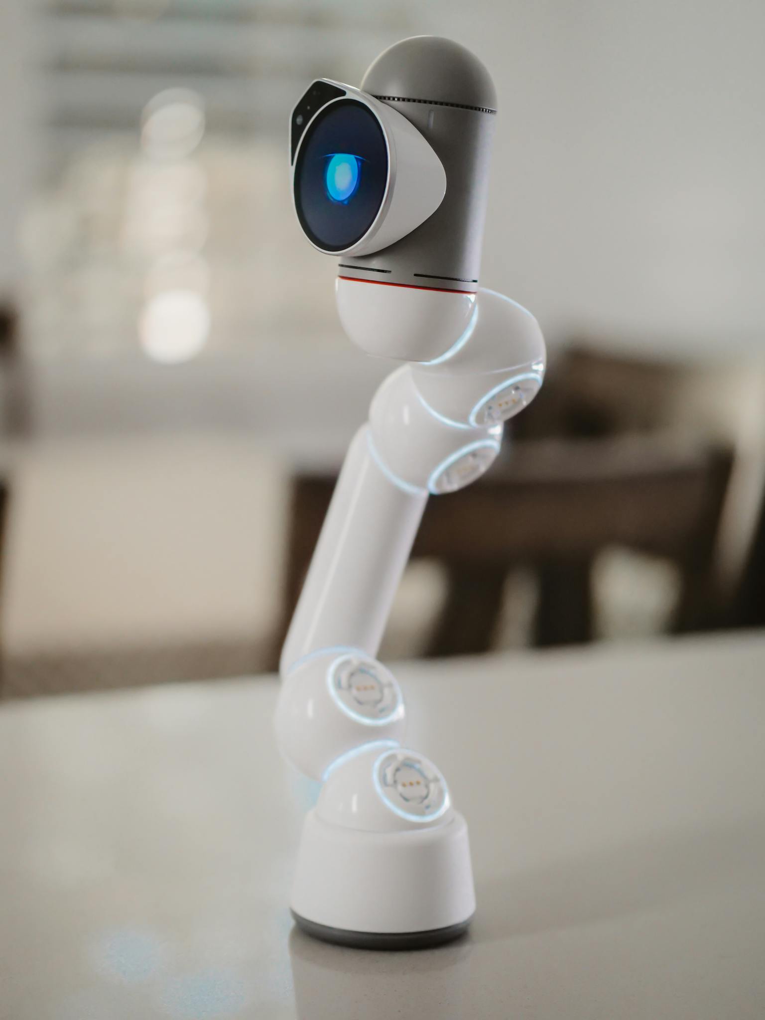 Modern robotic arm with blue sensor, showcasing futuristic technology indoors.